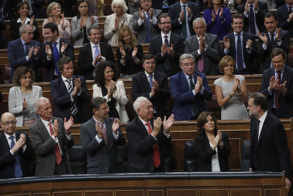 El líder del PP y presidente del Gobierno en funciones, Mariano Rajoy (d) es aplaudido por los diputados de su partido tras su intervencion, en el debate de su investidura, esta tarde en la Cámara Baja.