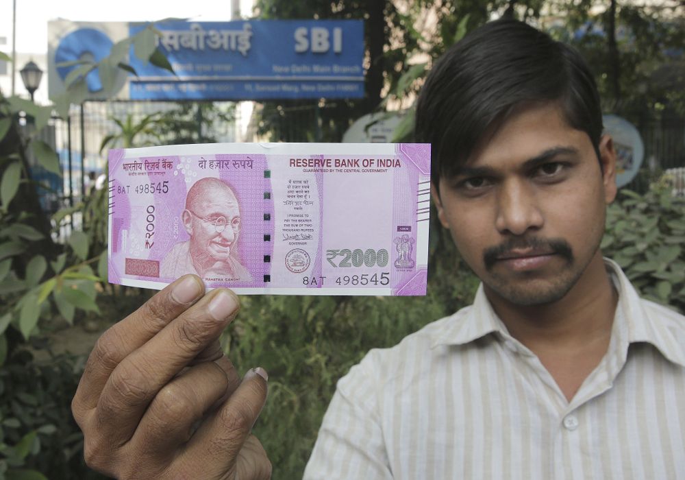 Un ciudadano muestra un billete nuevo de 2.000 rupias tras cambiarlo por los billetes antiguos en un banco en Nueva Delhi (India) hoy, 10 de noviembre de 2016.
