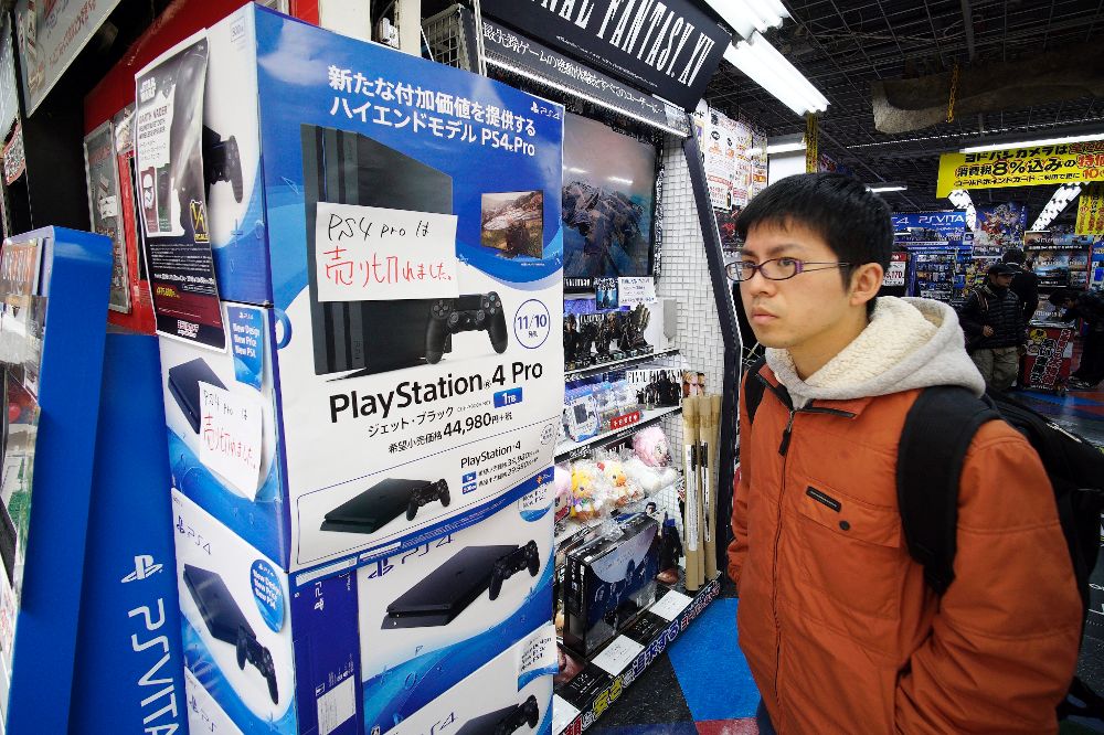 Un cliente pasa junto a varias unidades de la nueva consola PlayStation 4 Pro en una tienda de electrónica en Tokio (Japón).