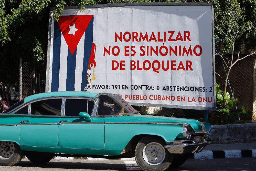 Un auto pasa junto a un cartel alusivo al bloqueo de Estados Unidos contra Cuba.