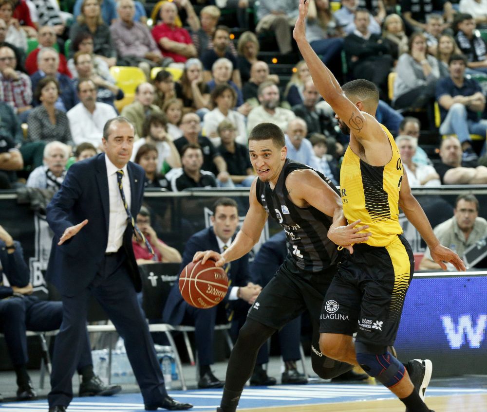 El jugador del Retabet Bilbao Basket, Scott Bamforth (c), disputa un balón con el jugador del Iberostar Tenerife Davin White (d), en presencia del entrenador Txus Vidorreta (i), durante un partido correspondiente a la liga Endesa disputado en el BilbaoArena.