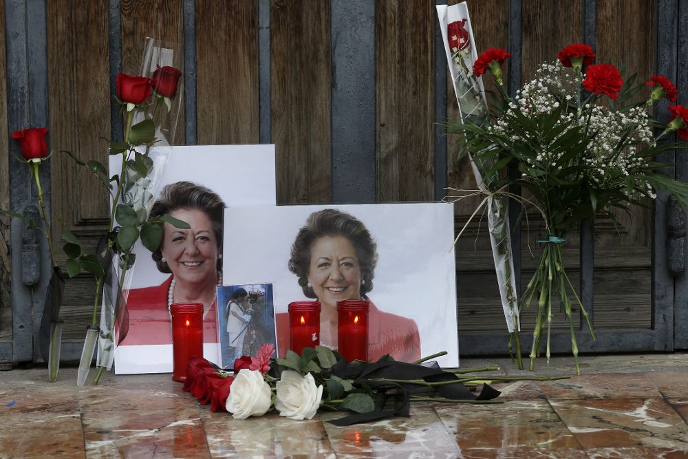 Fotografías y flores colocadas por personas anónimas en uno de las puertas del Ayuntamiento de Valencia en memoria de la exalcaldesa Rita Barberá.