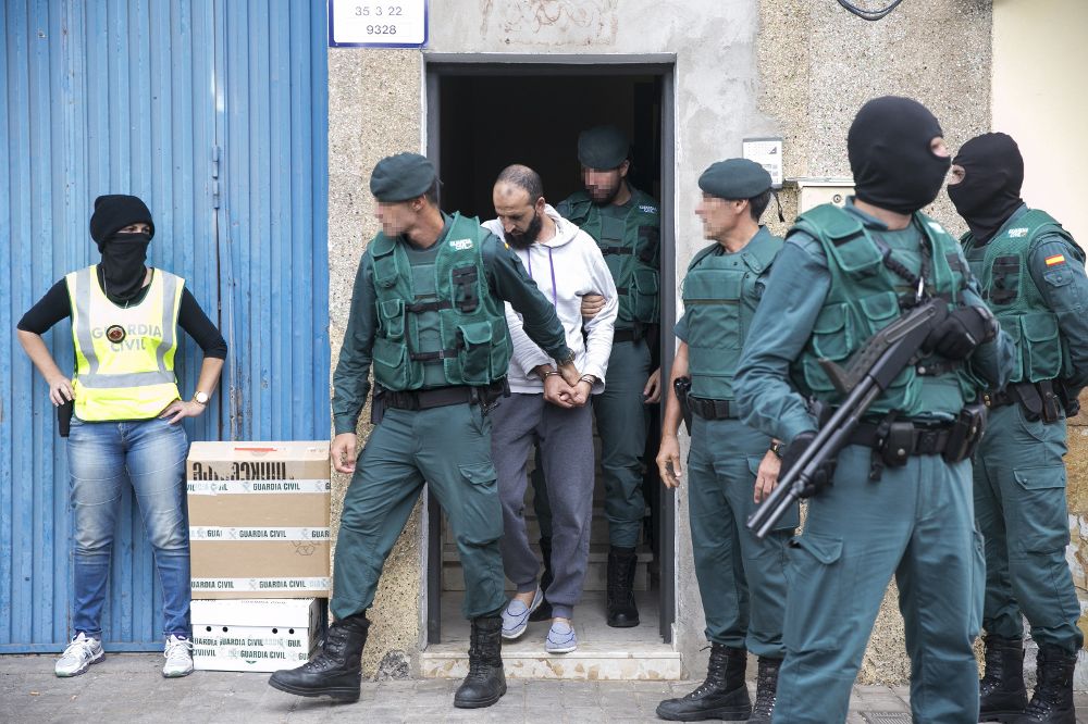 El presunto yihadista detenido hoy en el aeropuerto de Adolfo Suárez Madrid-Barajas, es trasladado por agentes de la Guardia Civil tras el registro a su vivienda en el número 16 de la calle Tinajo.