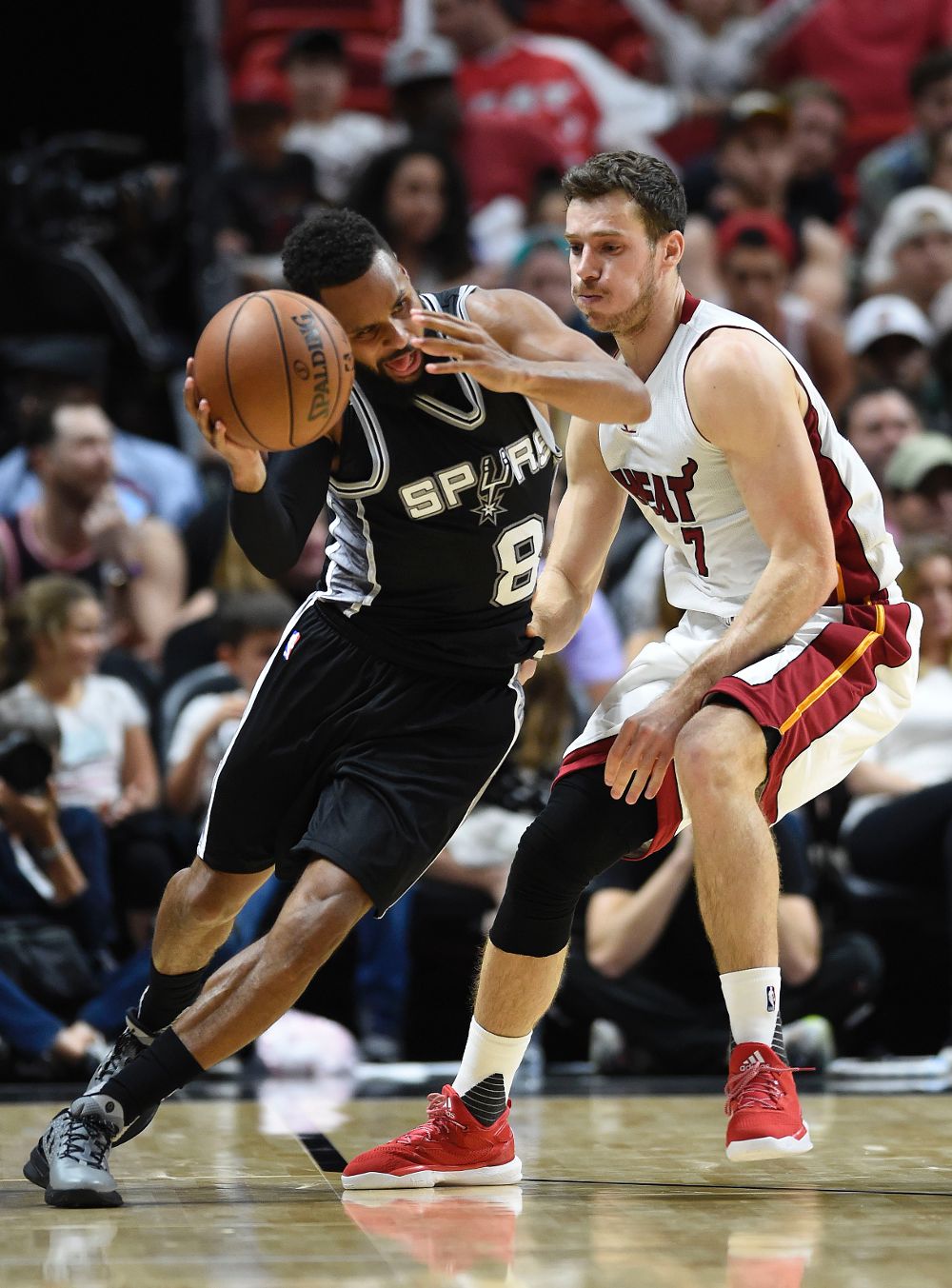 El jugador Patty Mills (i) de los Spurs disputa el balón con Goran Dragic (d) de los Heat.