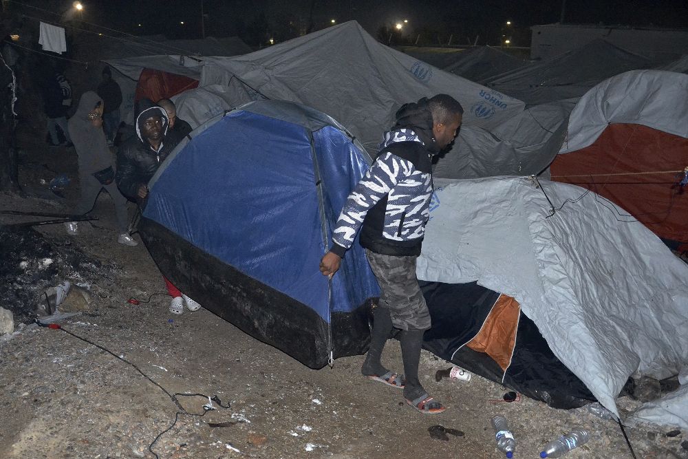Refugiados y migrantes trasladan sus tiendas de campaña durante un incendio en el campamento de refugiados en Lesbos (Grecia) el 25 de noviembre de 2016. 