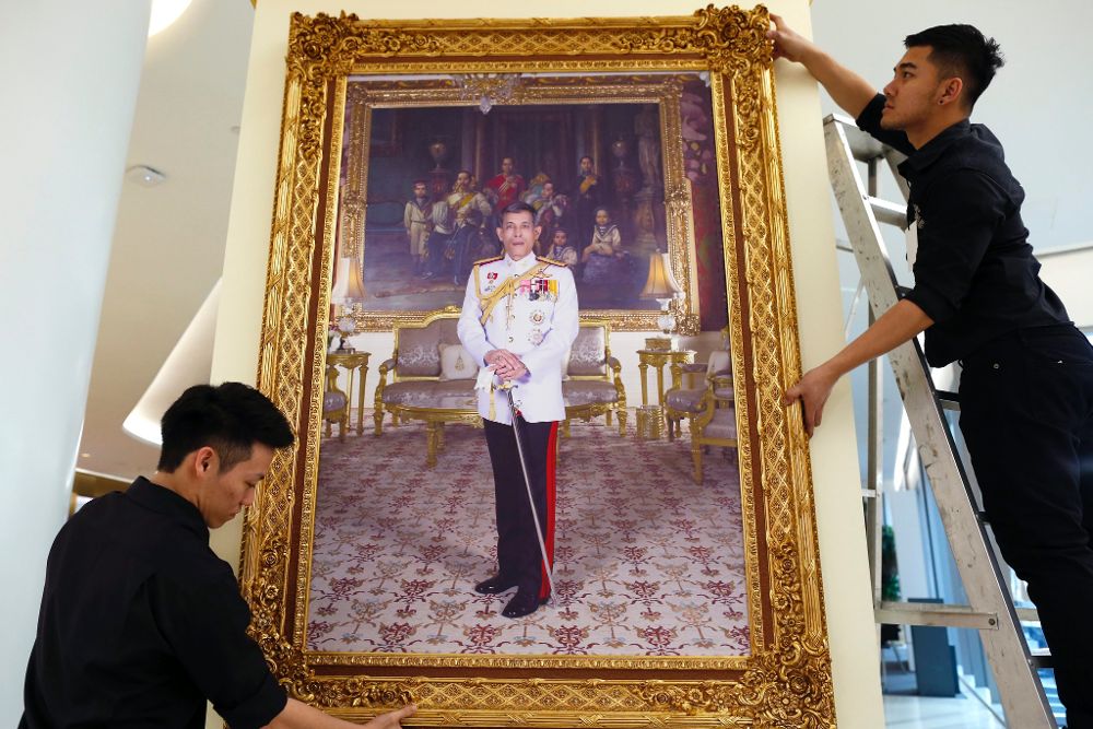 Dos empleados colocan un retrato del rey Vajiralongkorn en un centro comercial tras su proclamación real con el nombre de Rama X, en Bangkok, Tailandia.