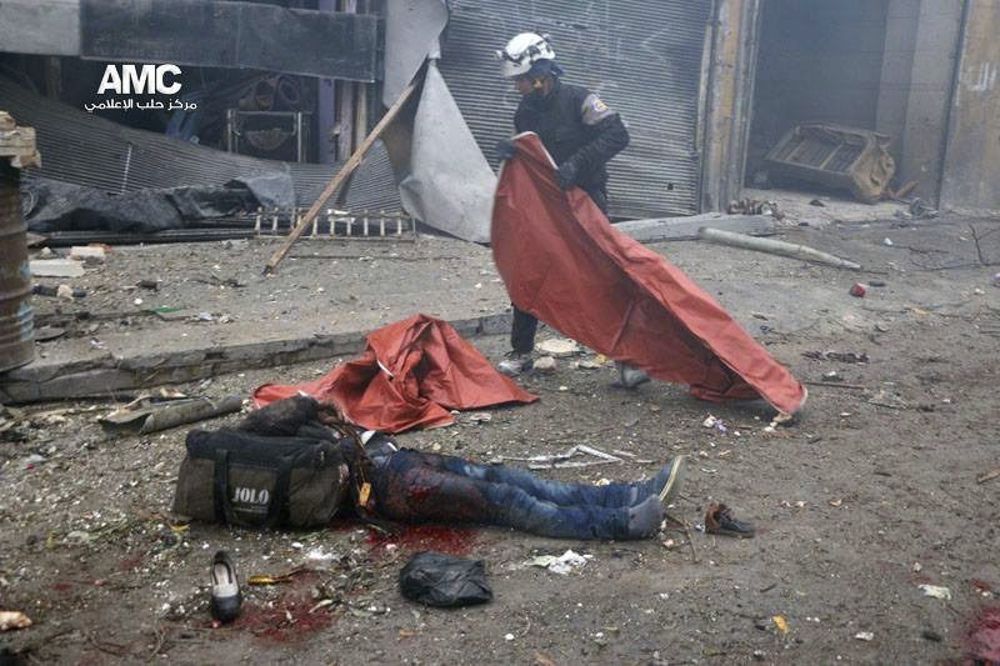 Fotografía cedida por Alepo Media Center, que muestra a un miembro de la Defensa Civil, conocidos como cascos blancos, mientras cubre el cuerpo de un fallecido tras el impacto de una bomba en el barrio de Yeb al Quebeh en Alepo.