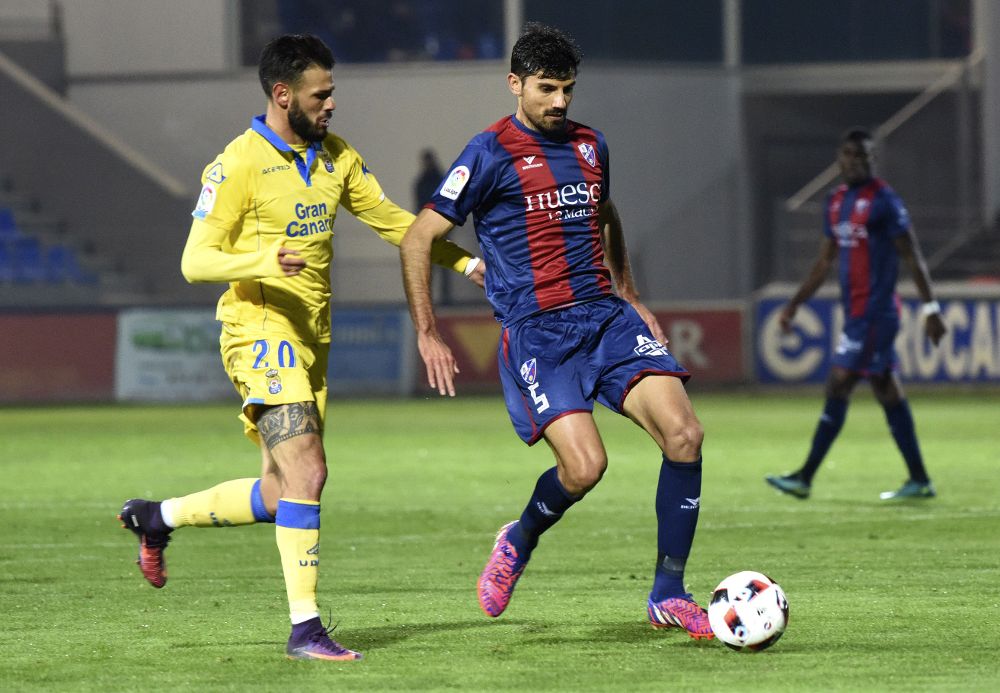 El centrocampista del Huesca Juan Aguilera (d) disputa un balón con el delantero Tyronne del Pino (i), de Las Palmas.