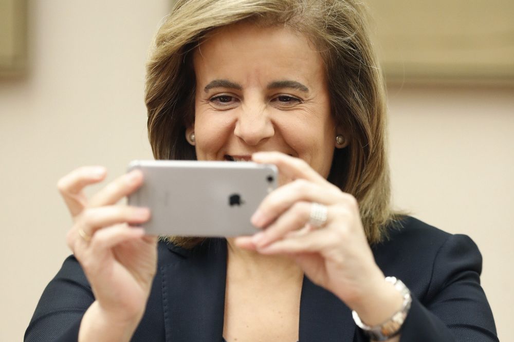 La ministra de Empleo, Fátima Báñez, hace una foto con su teléfono móvil a los fotógrafos.