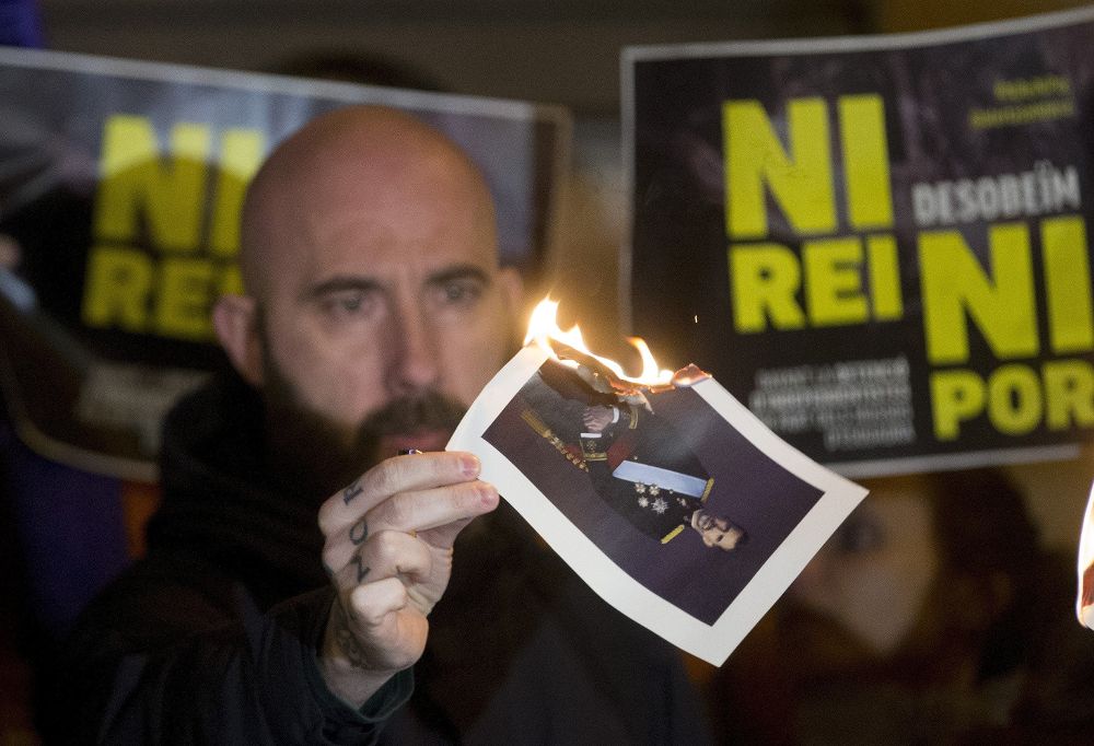 El concejal de la CUP en el Ayuntamiento de Barcelona Josep Garganté quema una foto del Rey en la concentración convocada la pasada noche en la capital catalana en solidaridad con los cinco investigados.