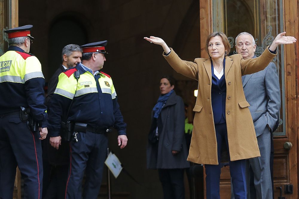 La presidenta del Parlament, Carme Forcadell, saluda a los asistentes antes de entrar, acompañada por su marido, Bernat Pegueroles (d), al Tribunal Superior de Justicia de Cataluña.