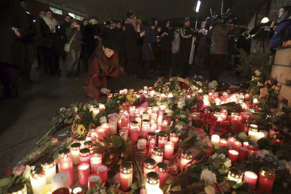Una mujer enciende una vela en el lugar del atentado que ayer dejó doce víctimas y numerosos heridos en un mercadillo de Navidad de Berlín, Alemania.