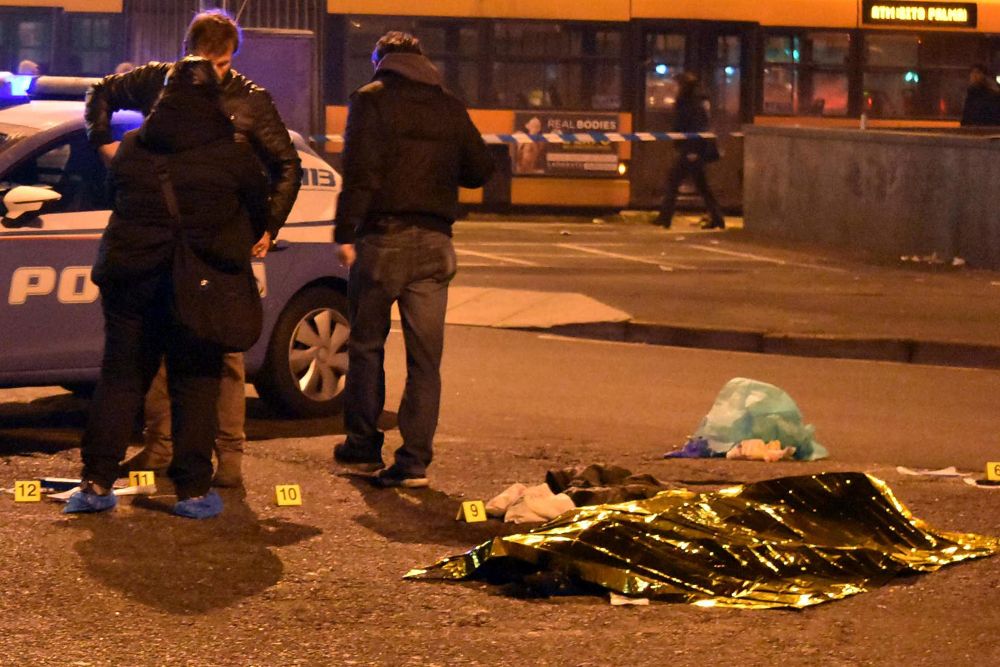 Policías permanecen junto al cuerpo sin vida del tunecino de 24 años sospechoso de cometer el atentado de Berlín, Anis Amri, tras ser abatido en un tiroteo con la Policía italiana en la ciudad de Milán.