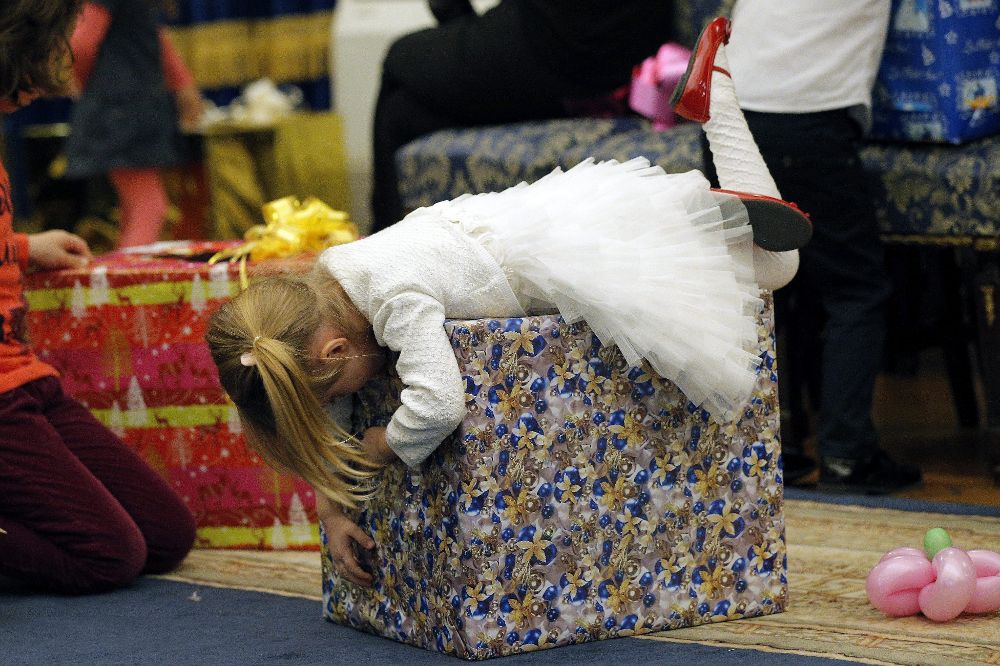 Una niña se abalanza sobre su regalo de Navidad.