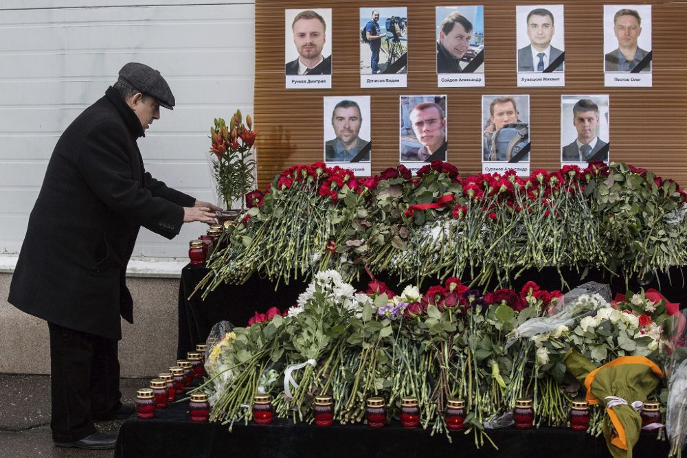 Un hombre deja flores ante los retratos de los periodistas rusos muertos en el accidente del avión militar ruso Tu-154, que se estrelló en el mar cerca de Sochi (Rusia).