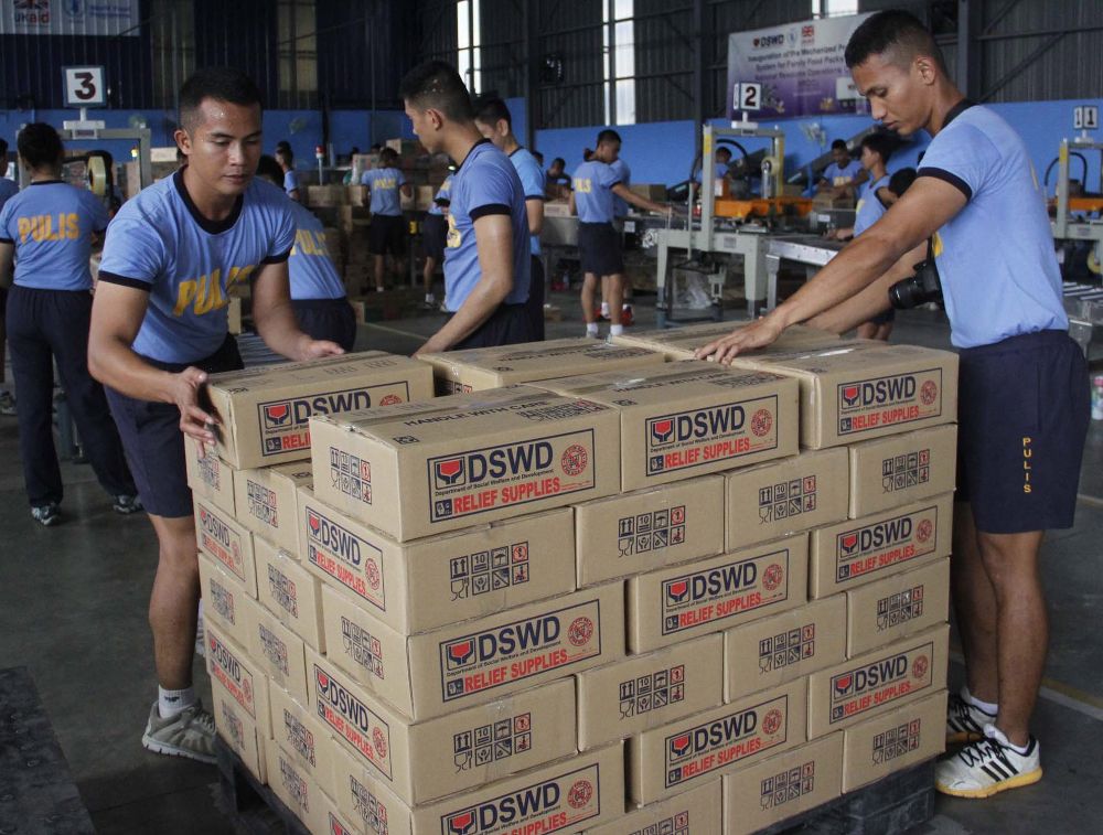 Varios policías transportan cajas con productos de primera necesidad en la ciudad de Pasay, al sur de Manila (Filipinas).