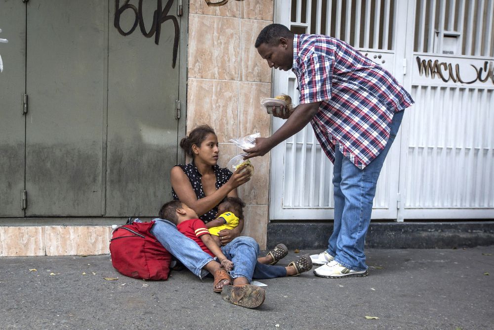 Un grupo de jóvenes reparte comida comprada y preparada por ellos mismos a personas en situación de calle e indigencia, en Caracas.