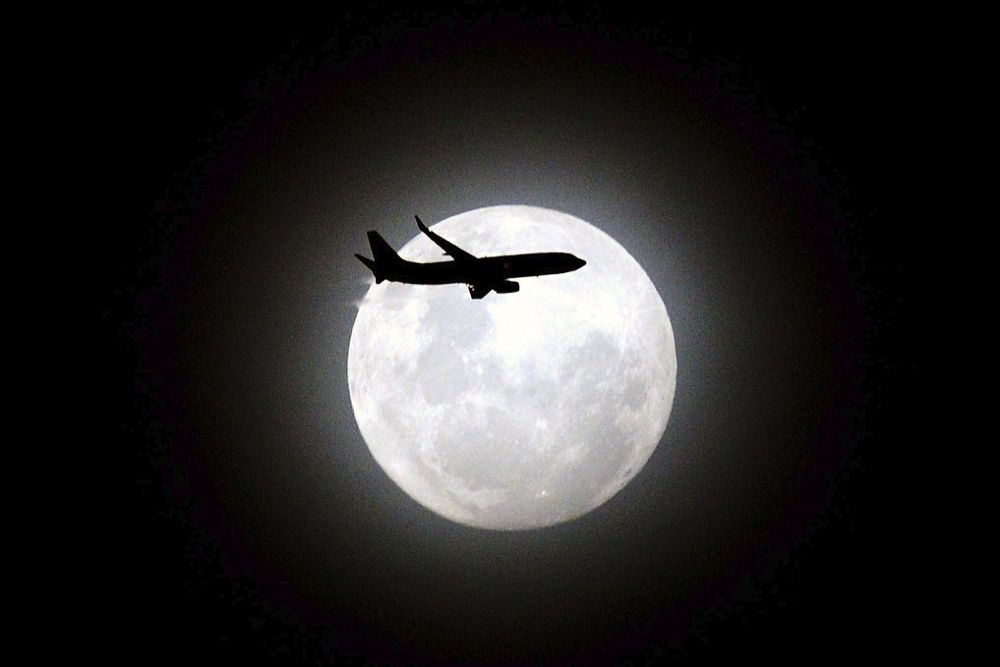 Un avión de pasajeros pasa delante de la tercera y última luna en perigeo sobre la playa de Maroubra en Sídney (Australia) el13 de diciembre de 2016. 