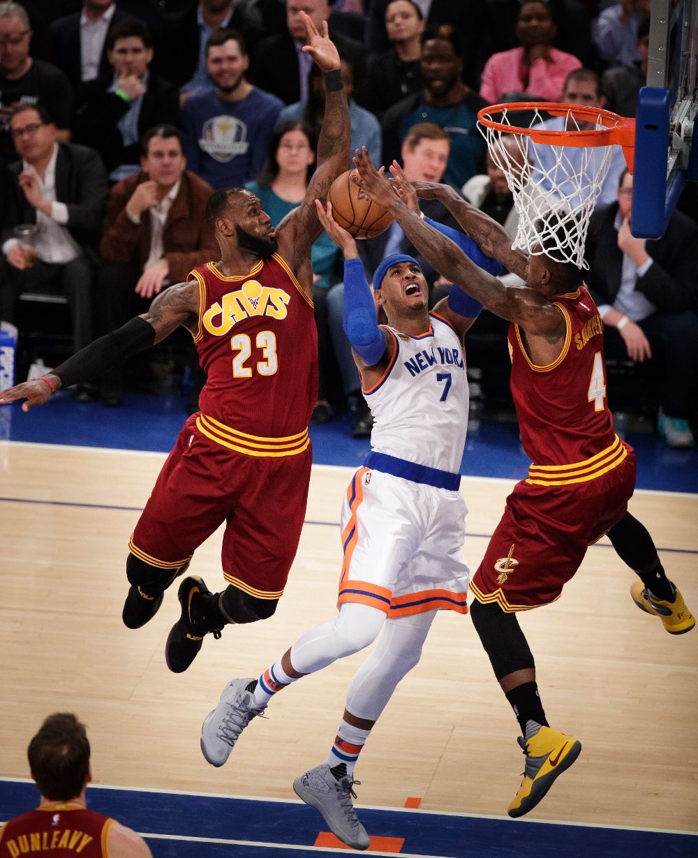 Carmelo Anthony (c) de New York Knicks salta para encestar en medio de LeBron James (i) e Imán Shumpert (d) de Cleveland Cavaliers.
