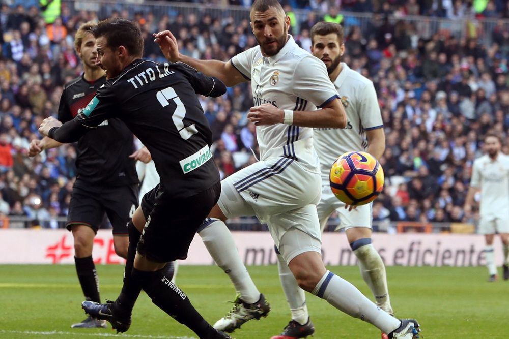 Benzema (c) pelea un balón con el defensa del Granada Tito (i) durante el partido de la décimo séptima jornada de Liga.