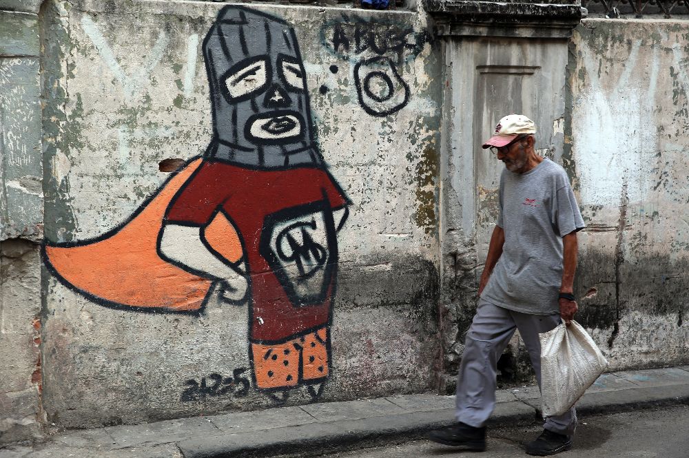 Un anciano camina junto a una pared con un grafiti en La Habana (Cuba).