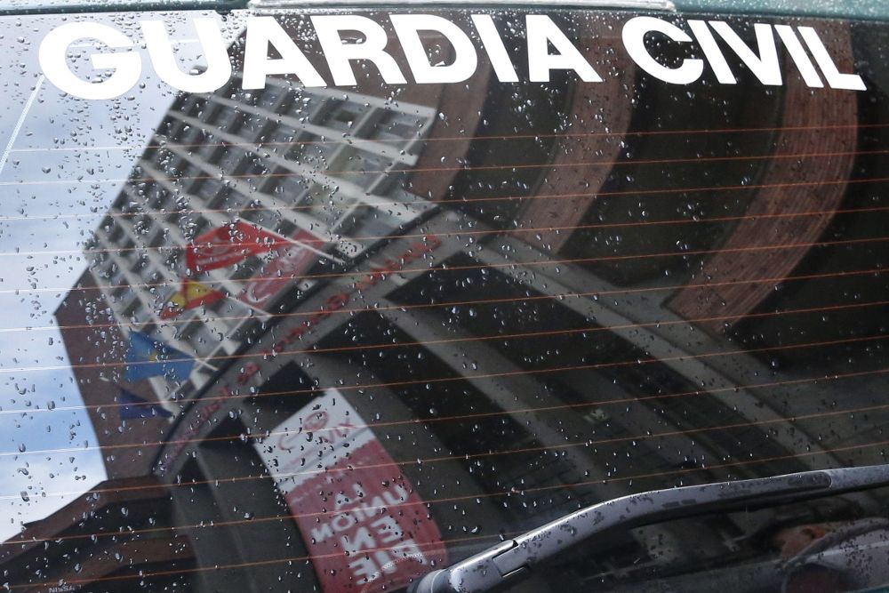 Reflejo de la sede central de UGT de Asturias en el cristal de un coche de la Guardia Civil.