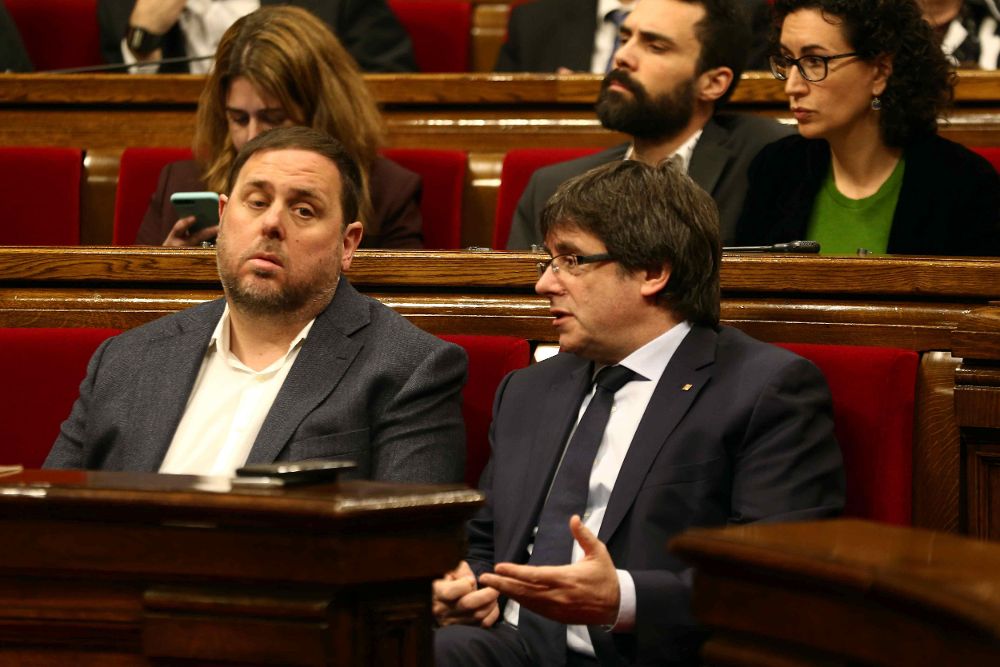 El presidente de la Generalitat, Carles Puigdemont (d), habla con el vicepresidente, Oriol Junqueras, en el Parlament.
