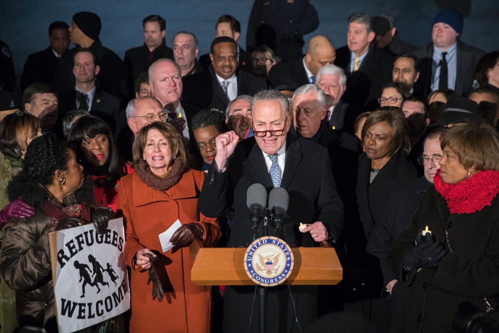 El líder del Senado de EE.UU. Chuck Schumer (c), la líder de la minoría de la Cámara de EE.UU. Nancy Pelosi (c-i) e integrantes del Senado y la Cámara, el lunes, en una manifestación contra la prohibición de inmigración.