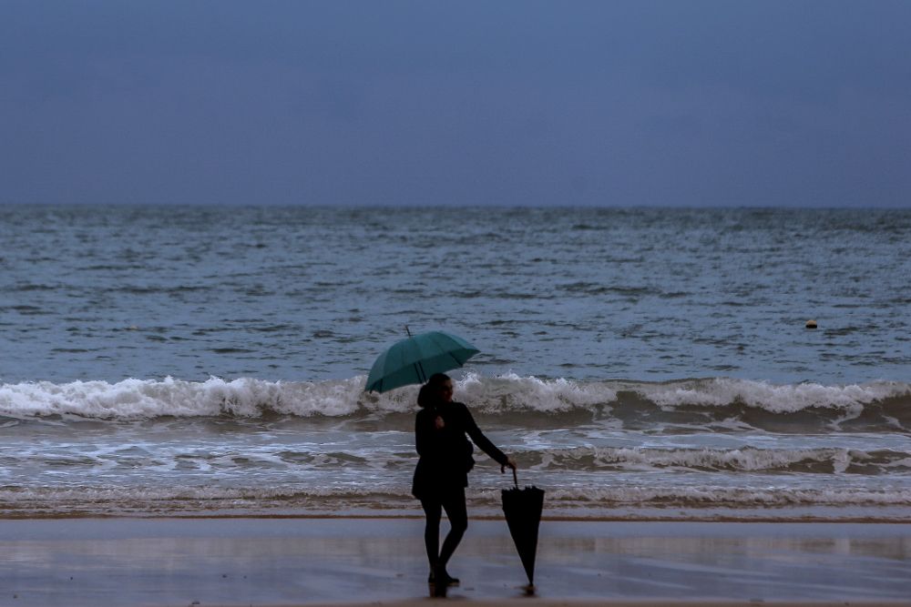 Una mujer bajo la lluvia en la playa de La Concha, de San Sebastián.