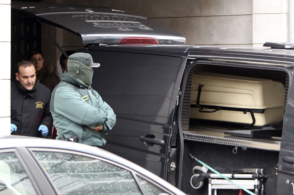 Un agente de la Guardia Civil permanece junto al furgón de los servicios funerarios, durante el traslado de los cadáveres de las dos mujeres asesinadas.