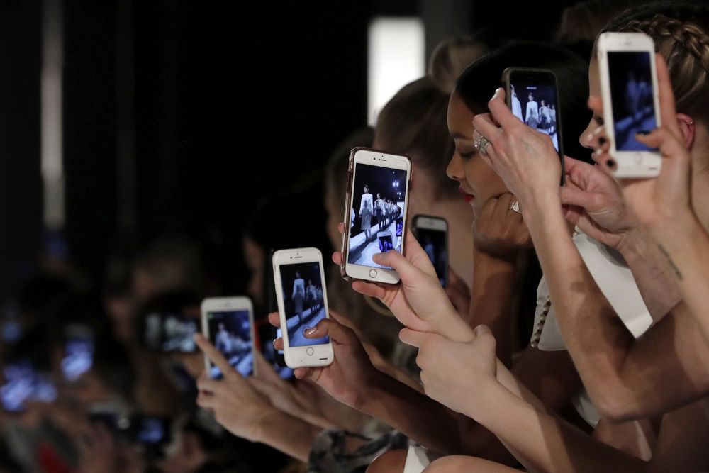 Varias personas realizan fotografías y vídeos con sus teléfonos móviles.