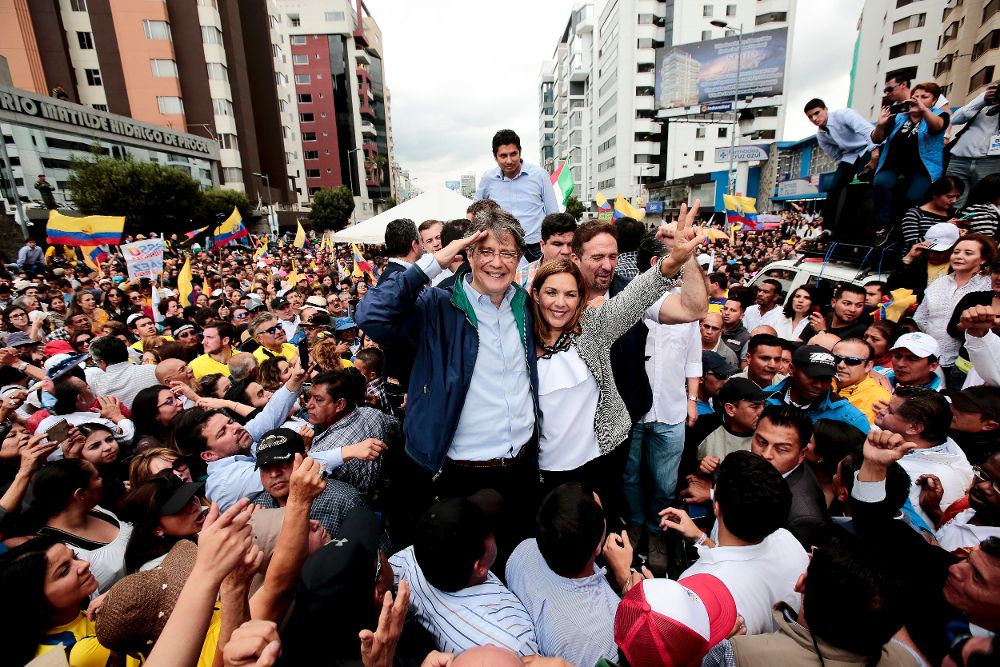 El candidato presidencial ecuatoriano de oposición, Guillermo Lasso (c-i), saluda a sus seguidores junto a su esposa en Quito.