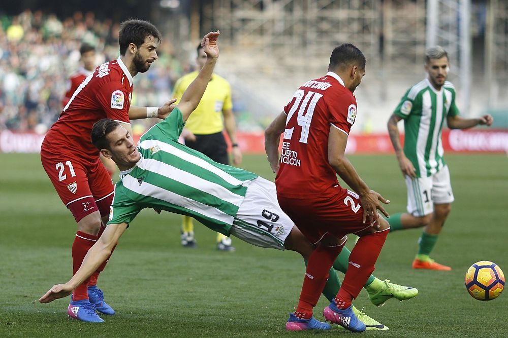 El jugador del Betis Alex Alegría (c) cae al suelo presionado por los defensas argentinos del Sevilla Nico Pareja (i) y Gabriel Mercado (d) durante el partido.