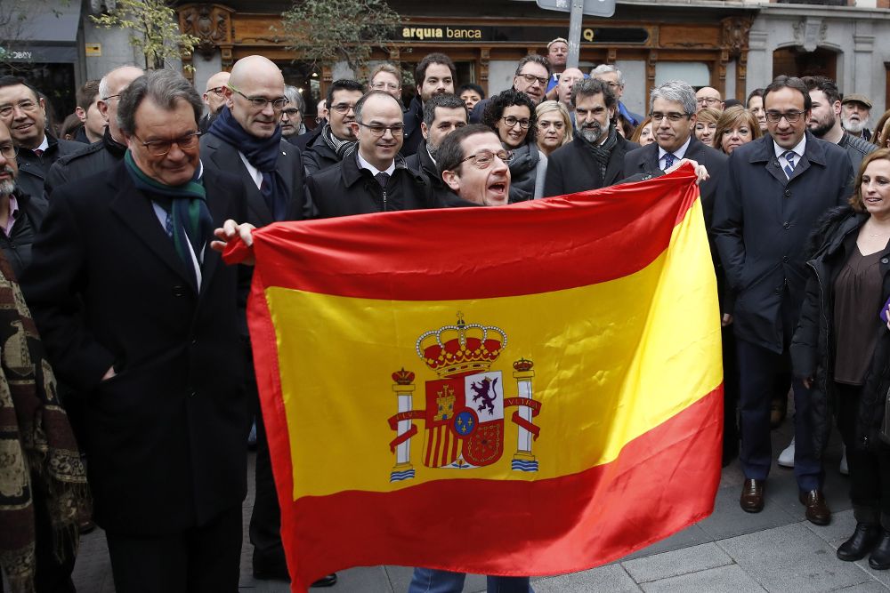 Un hombre despliega una bandera española ante la presencia del expresidente de la Generalitat Artur Mas (iz), entre otros, durante el recorrido a pie que hicieron hacia la sede del Tribunal Supremo.