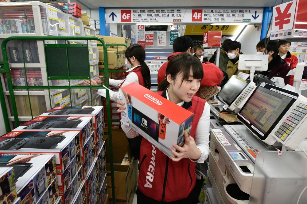 La dependienta de una tienda de electrónica en Tokio, (Japón) hoy, viernes, vendiendo la nueva consola de videojuegos.