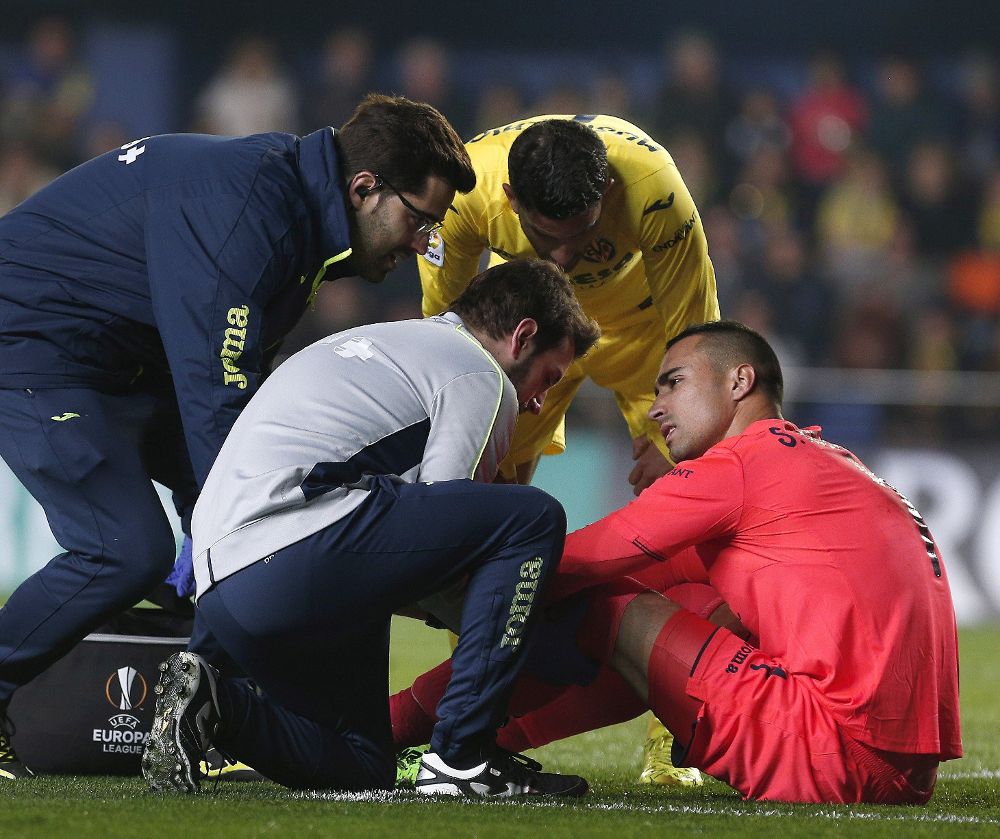 El portero del Villarreal Sergio Asenjo (d) es asistido tras lesionarse.
