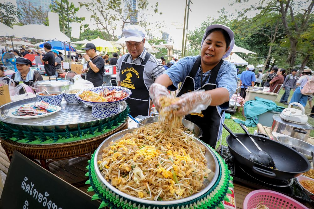 Una mujer cocina noodles en un puesto en Bangkok, Tailandia.