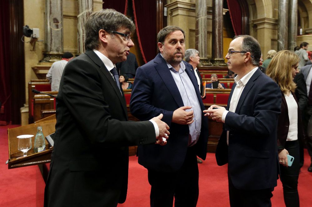 Carles Puigdemont (i), Oriol Junqueras (c), y el portavoz de JxSí, Jordi Turull, conversan en el Parlament de Catalunya que debate sobre cómo aludir al referéndum en los presupuestos del Govern.