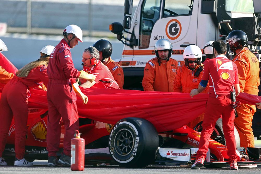 Mecánicos de Ferrari y comisarios de pista ayudan a retirar el coche del piloto de Ferrari Kimi Räikkönen tras la salida de pista que sufrió durante la última jornada de entrenamientos en el Circuito de Barcelona.