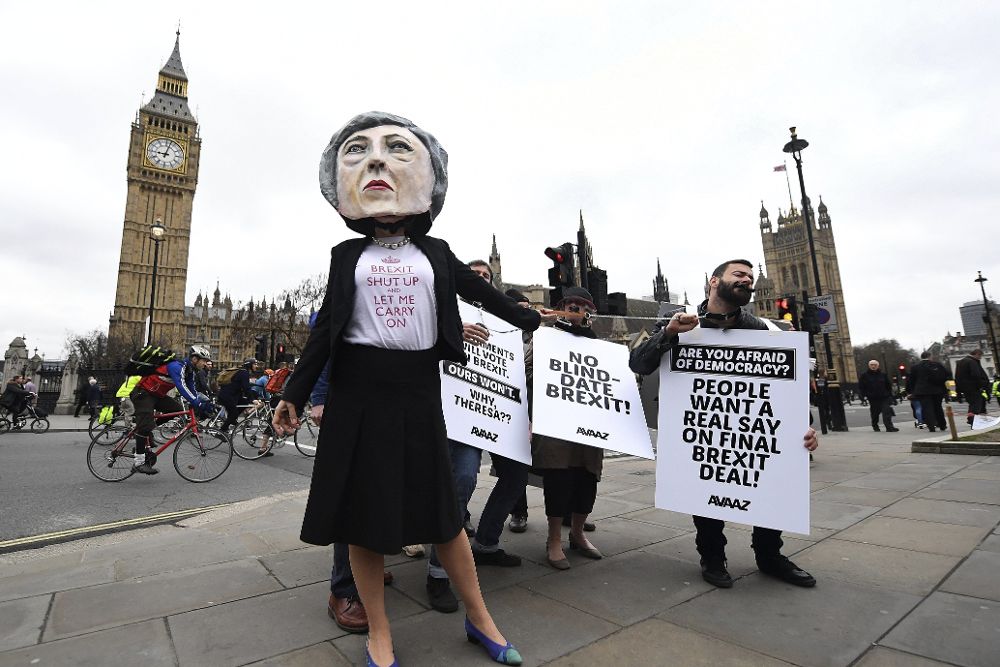 Una manifestante disfrazada de la primera ministra británica, Theresa May (i), posa junto a otros que sostienen pancartas que rezan "27 Parlamentos votarán sobre el 'brexit' el nuestro no, ¿por qué Theresa?", "Ninguna cita a ciegas con el brexit" y "¿Tienes miedo a la democracia? La gente quiere voz en la decisión final sobre el brexit" .