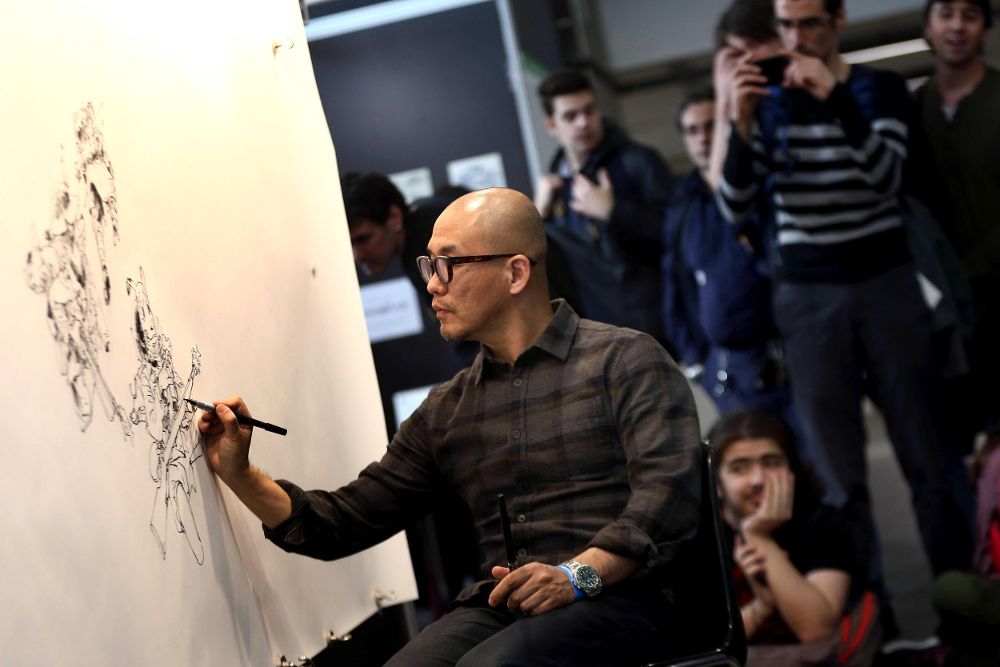 El artista coreano Kim Jung Gi, que se distingue por sus actuaciones de dibujo en directo, con un rotulador sobre una gran superficie de papel en el Salón del Cómic de Barcelona.