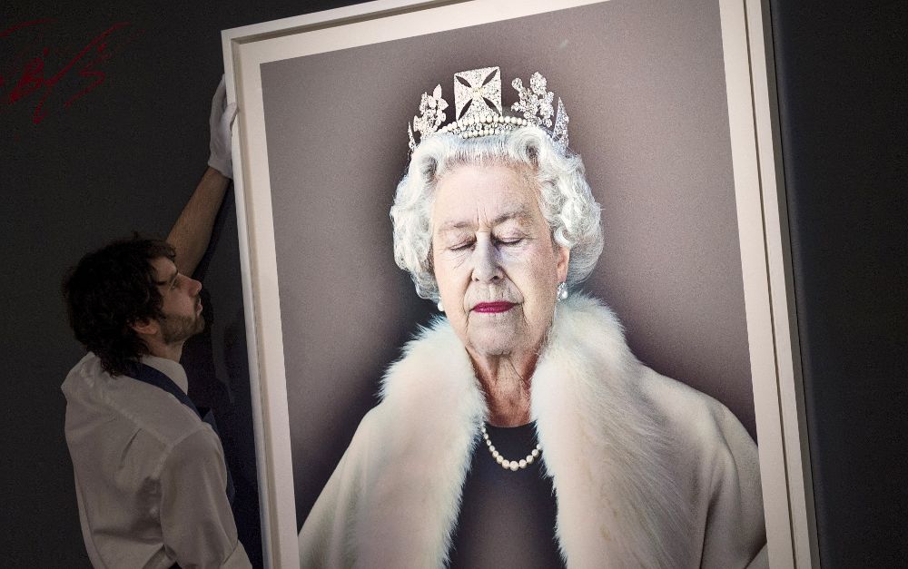 Un trabajador coloca el retrato de la reina Isabel II de Inglaterra titulado "Levedad del ser", obra del fotógrafo británico Chris Levine, durante la presentación a los medios de la próxima subasta que celebrará la casa Sotheby's en Londres el próximo 5 de abril, en Londres, Reino Unido, hoy, 31 de marzo de 2017.