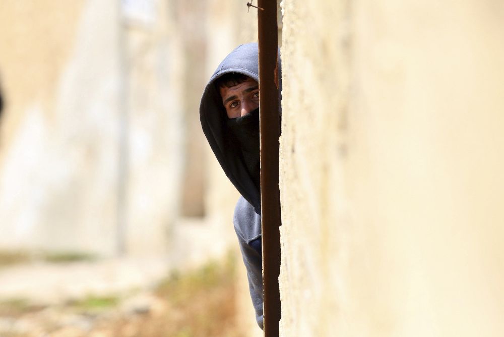 Un palestino observa escondido a los soldados israelíes.