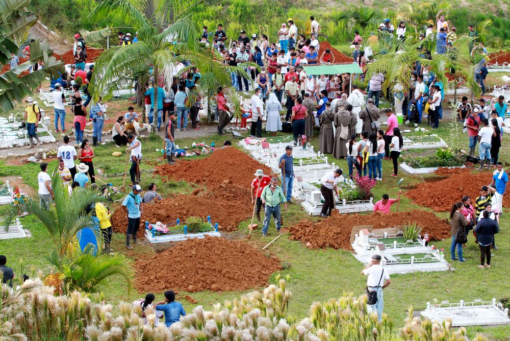 Un grupo de personas asiste a un entierro colectivo.