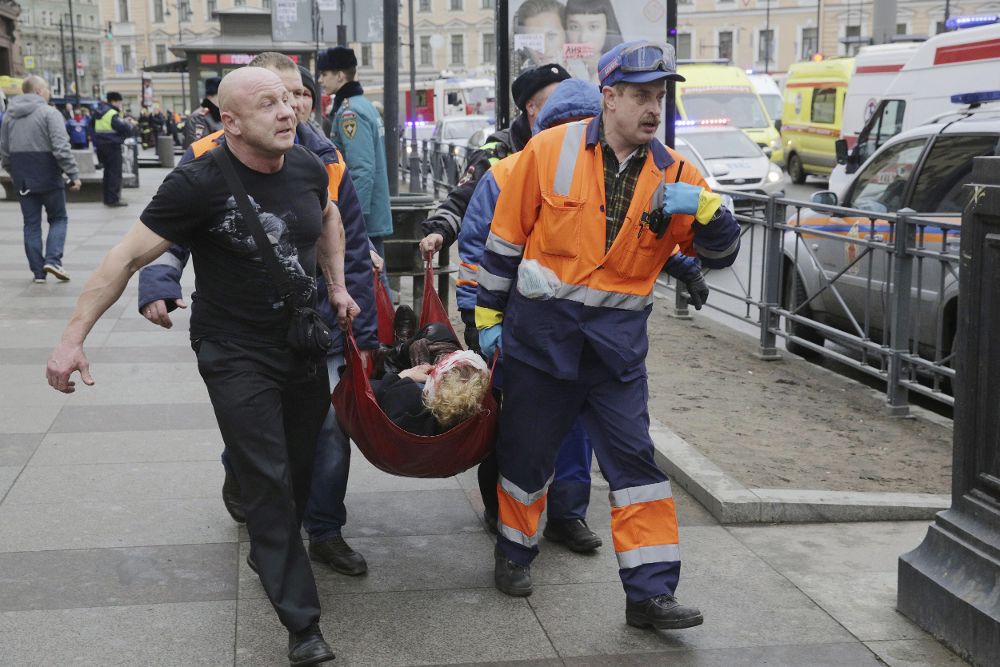 Bomberos y trabajadores de los servicios de emergencias transportan a una mujer, víctima del atentado terrorista.