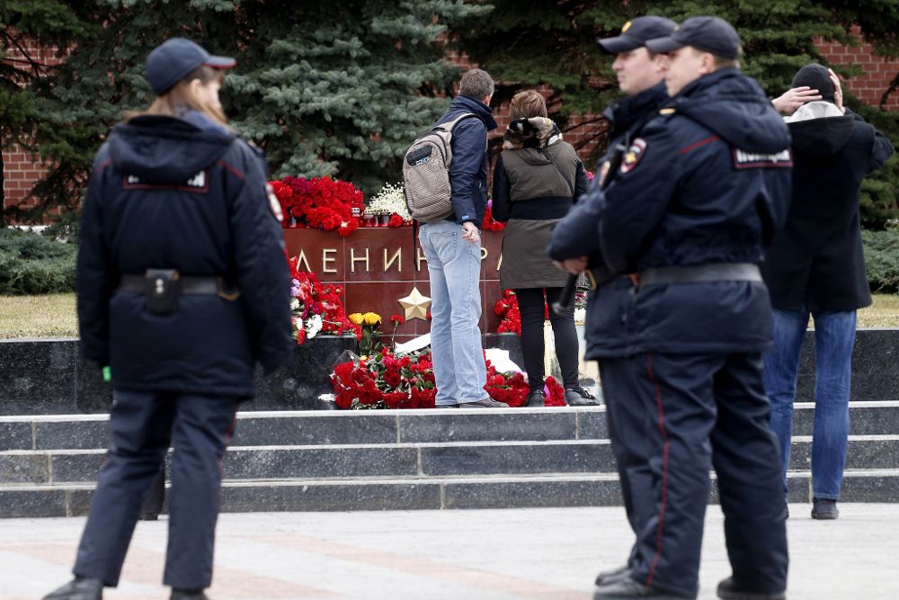 Policías rusos patrullan cerca de los ramos de flores dejados en memoria de las víctimas del atentado en el metro de San Petersburgo en el monumento conmemorativo de Leningrado, cerca del Kremlin, en Moscú (Rusia) hoy, 4 de abril de 2017, un día después del ataque.