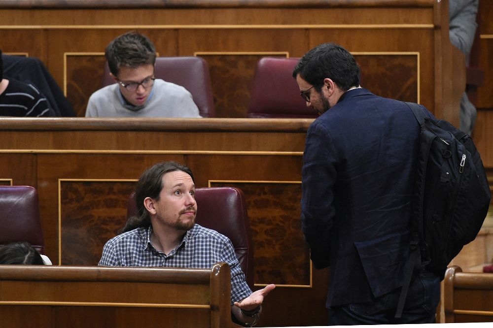 El secretario general de Podemos, Pablo Iglesias (i), conversa con el líder de IU, Alberto Garzón (d), esta tarde durante el pleno del Congreso de los Diputados.