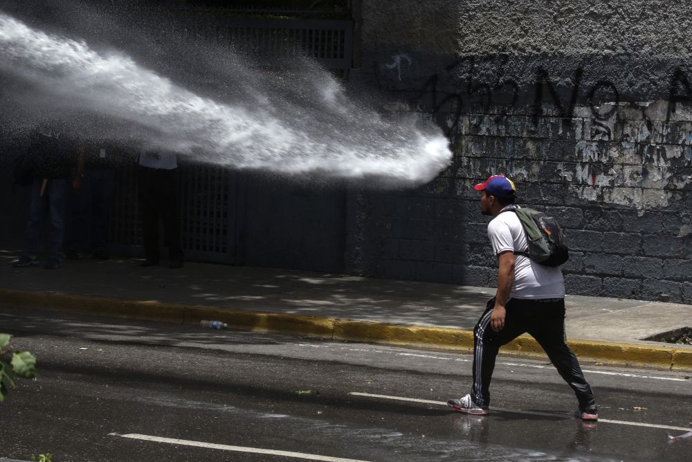 Un manifestante opositor se enfrenta a integrantes de la Policía Nacional Bolivariana (PNB) durante una manifestación.