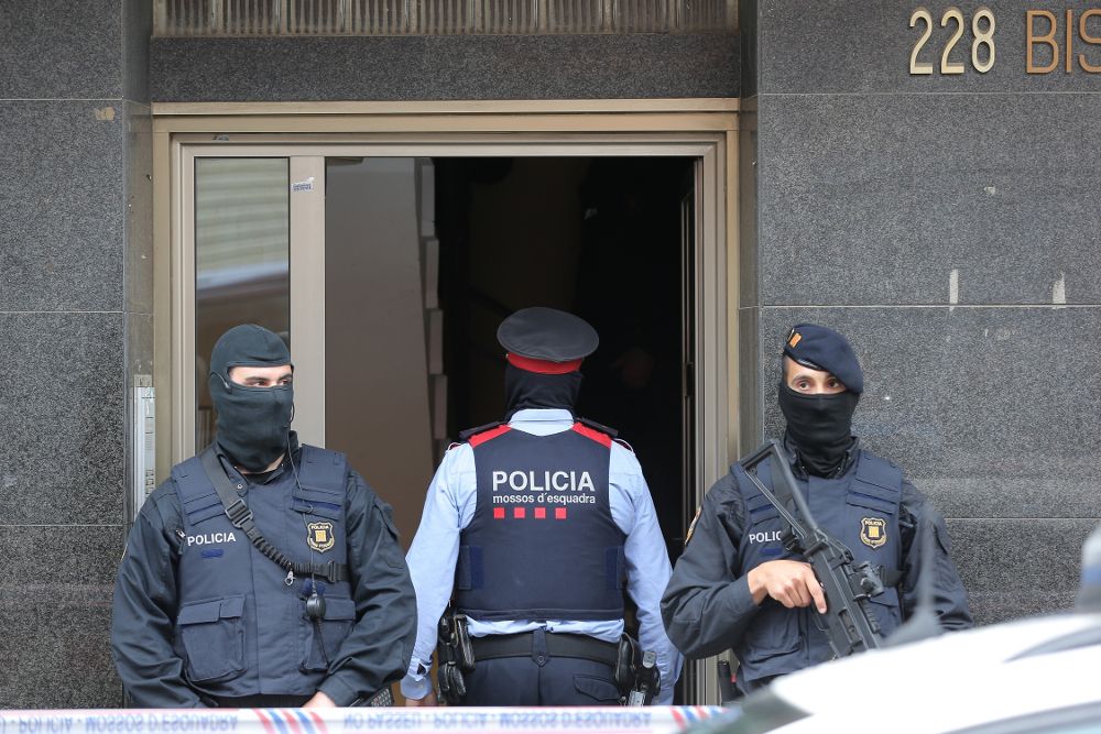 Agentes de los Mossos d'Esquadra custodian la entrada de la vivienda de Terrassa (Barcelona).