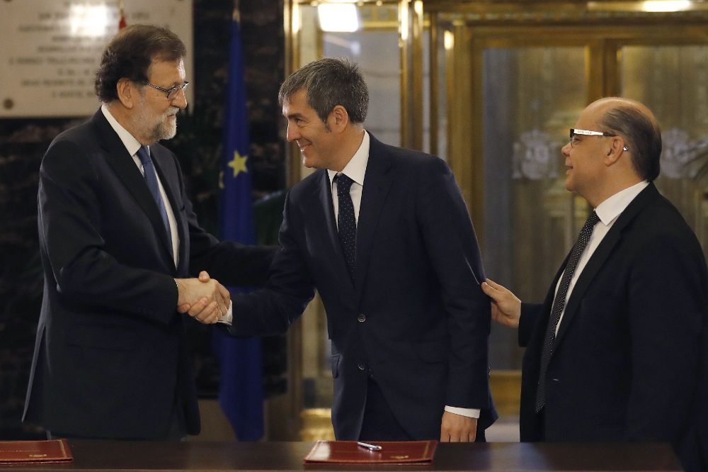Mariano Rajoy, durante firma con el secretario general de CC, José Miguel Barragán (d), del acuerdo suscrito entre sus dos partidos sobre los presupuestos generales del Estado de 2017, en un acto al que asiste el jefe del Ejecutivo canario, Fernando Clavijo (c).